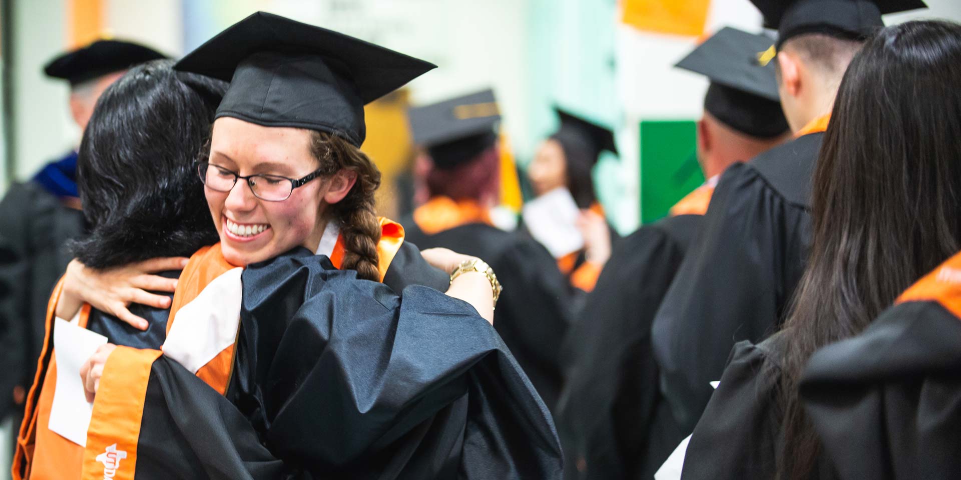 Jindal School bachelor's in business administration graduate hugging a friend on UT Dallas commencement day